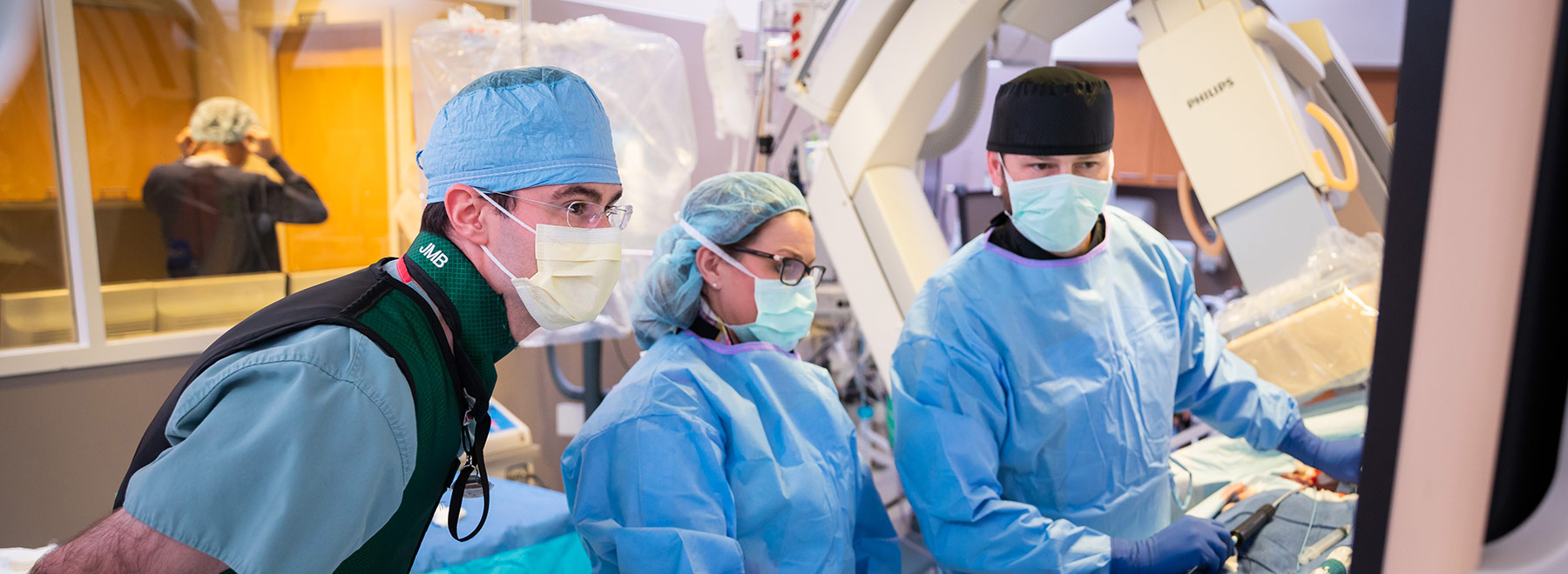 Three gowned people in procedure room Three gowned people in procedure room